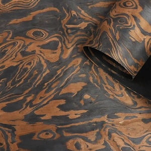 May include: Close-up of a sheet of wood veneer with a dark brown and black marbled pattern. The wood has a natural, organic look and feel.