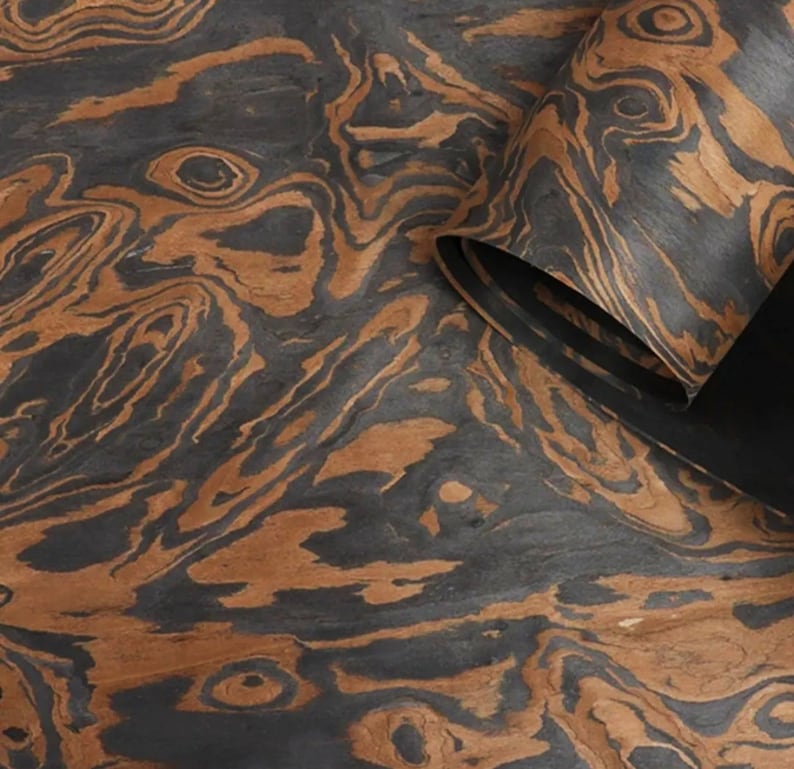 May include: Close-up of a sheet of wood veneer with a dark brown and black marbled pattern. The wood has a natural, organic look and feel.