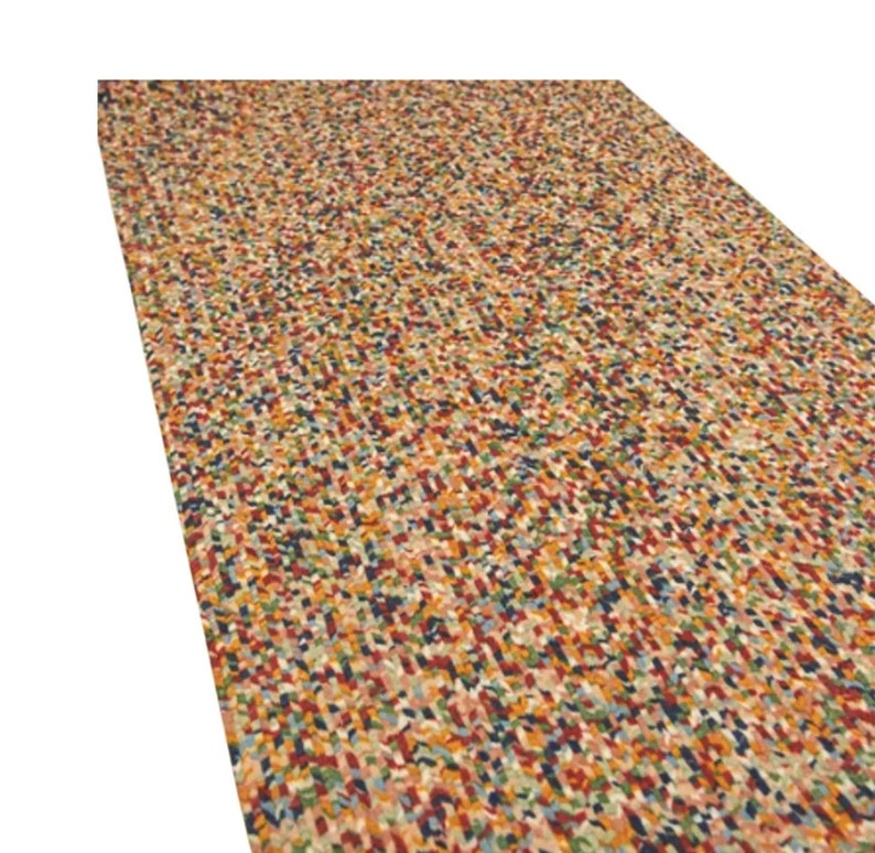May include: A rectangular rug with a speckled pattern. The rug features a mix of colors, including red, blue, green, yellow, and brown. The design is made up of small, irregular shapes, creating a textured appearance.