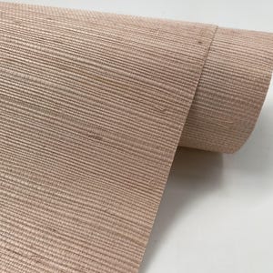 Puede incluir: Un rollo de papel tapiz texturizado rosa claro con un aspecto tejido.