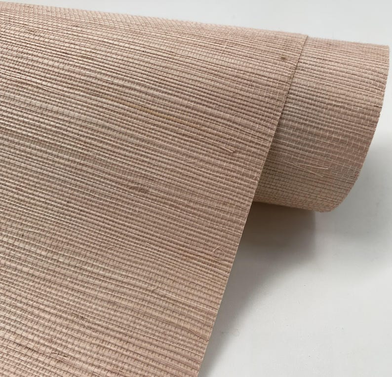 Puede incluir: Un rollo de papel tapiz texturizado rosa claro con un aspecto tejido.