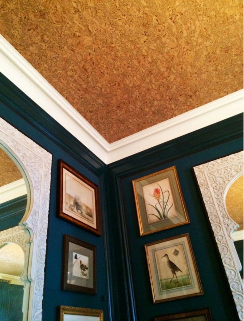 May include: A corner of a room with a cork ceiling and teal blue walls. The walls are decorated with framed botanical prints and a mirror with an ornate frame.