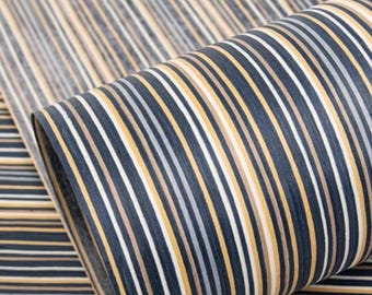 May include: A roll of fabric with a repeating pattern of vertical stripes in navy blue, white, gold, and gray. The fabric is partially rolled, revealing the pattern and texture of the material. The stripes vary in width and create a visually interesting design.
