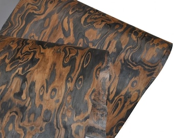 May include: A sheet of wood veneer with a dark brown and black swirling pattern. The wood has a natural, organic look.