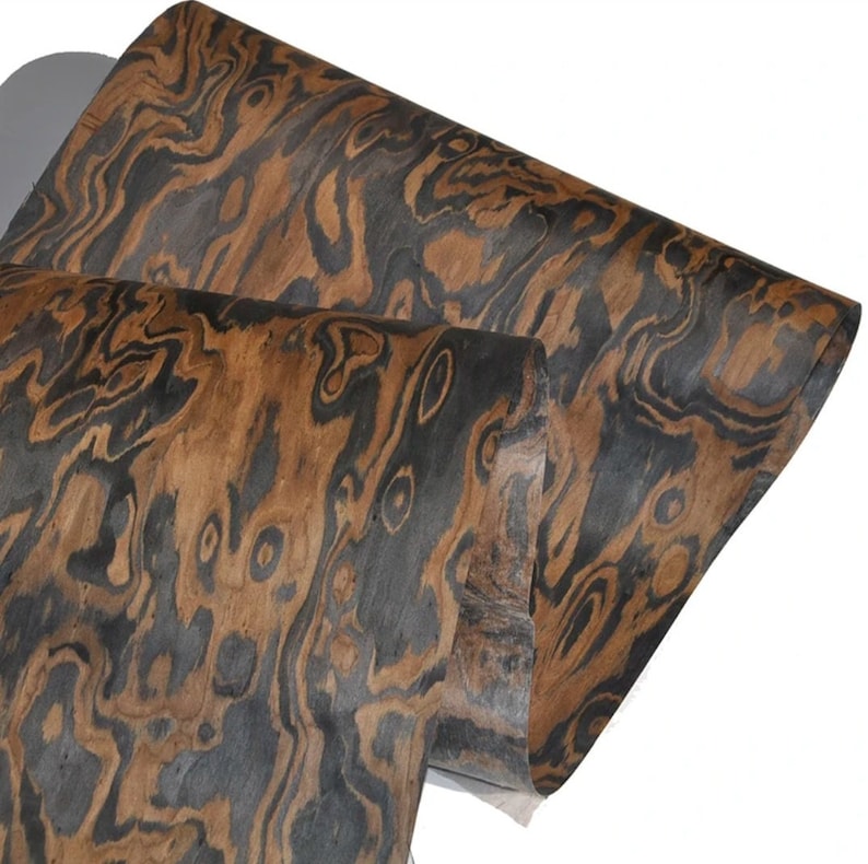 May include: A sheet of wood veneer with a dark brown and black swirling pattern. The wood has a natural, organic look.