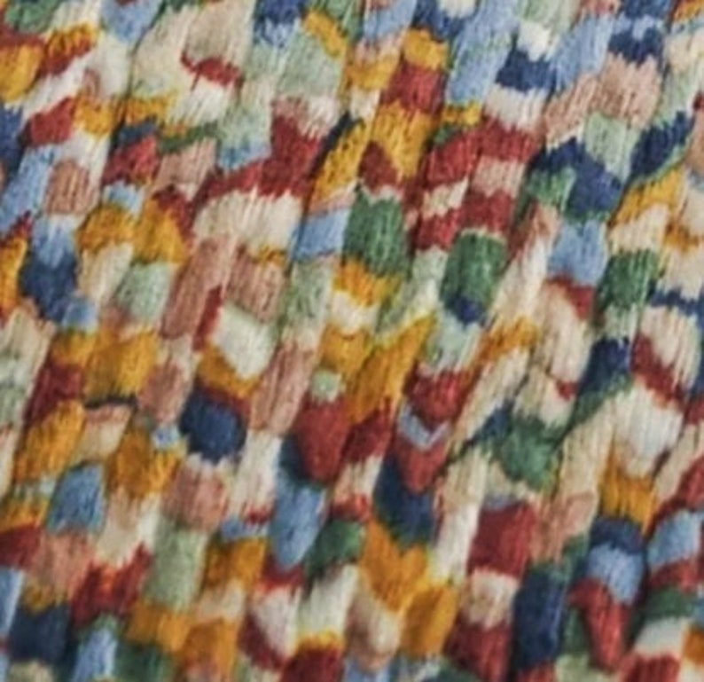 May include: Close-up of a colorful, textured rug. The rug features a pattern of interwoven threads in various colors, including red, blue, yellow, green, and white. The design is abstract and appears to be made of tightly packed, irregular shapes.