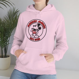 May include: Pink hoodie featuring a black and white image of Mickey Mouse in a red circle with the text "Mickey Mouse Est 1928".