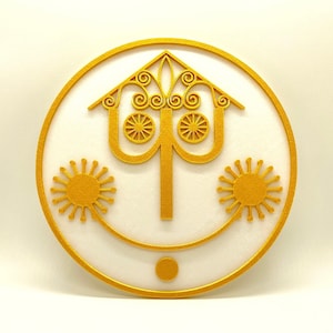 Könnte beinhalten: Eine goldfarbene, runde Wanddekoration mit einem stilisierten Design eines Baumes mit drei Ästen und Blättern. Der Baum ist von zwei stilisierten sonnenähnlichen Formen umgeben.
