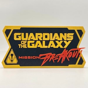 May include: A yellow and black card with the text "Guardians of the Galaxy Mission: Breakout!" in red and yellow lettering.