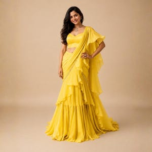 May include: A bright yellow ensemble featuring a sleeveless sweetheart neckline crop top paired with a matching floor-length skirt. The skirt is adorned with cascading vertical ruffles and a draped fabric panel that extends over one shoulder.