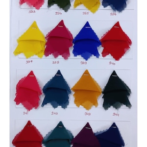 Puede incluir: Una carta de colores con diecis&eacute;is muestras de tela triangulares dispuestas en cuatro filas. Cada pieza de tela est&aacute; sujeta a un fondo blanco y etiquetada con un n&uacute;mero escrito a mano del 933 al 948, mostrando una variedad de colores vivos.