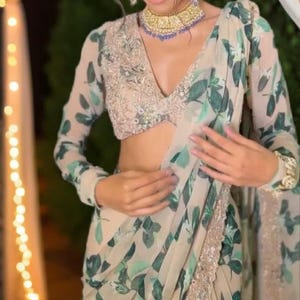 Bollywood-inspired georgette saree with sequin embroidery, ruffle work,Ready-to-wear with stitched blouse. Perfect for weddings & festivals.