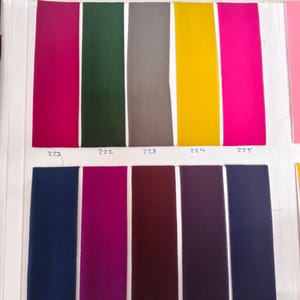 May include: A fabric color swatch card featuring ten vertical rectangular strips in various colors. The top row includes magenta, dark green, gray, yellow, and hot pink. The bottom row includes navy blue, plum, maroon, dark purple, and charcoal.