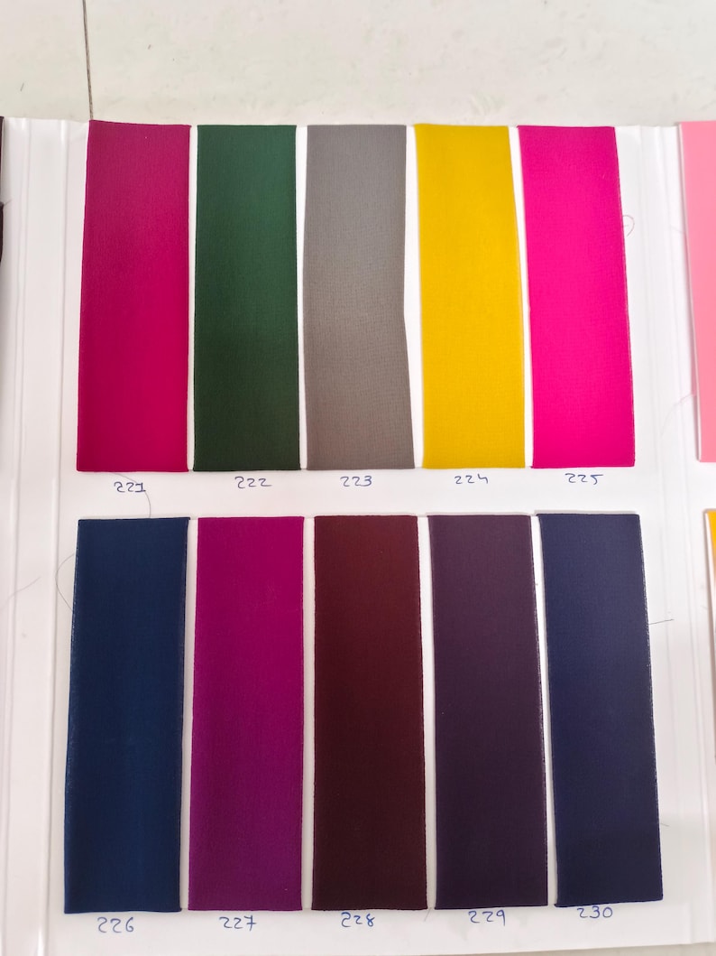 May include: A fabric color swatch card featuring ten vertical rectangular strips in various colors. The top row includes magenta, dark green, gray, yellow, and hot pink. The bottom row includes navy blue, plum, maroon, dark purple, and charcoal.