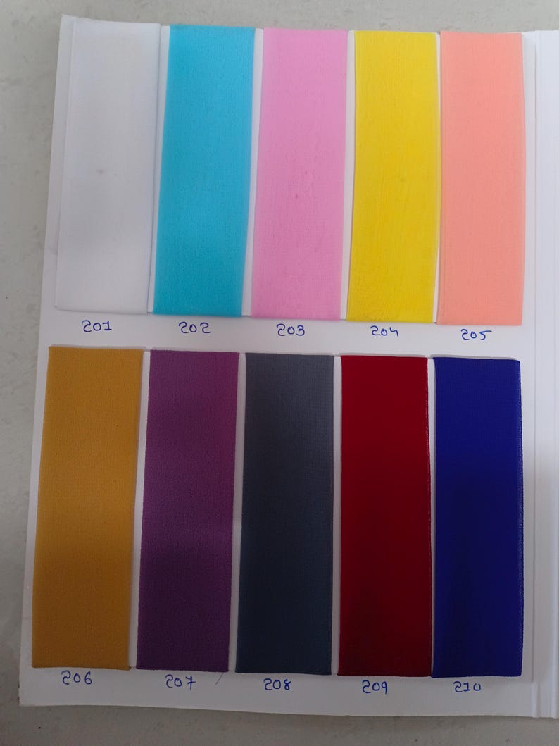 May include: A color swatch card featuring ten vertical strips of fabric in white, turquoise, pink, yellow, peach, mustard, purple, dark gray, red, and blue. Each strip is labeled with a handwritten number from 201 to 210 below the color sample.