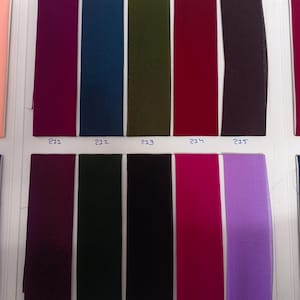 May include: A fabric swatch color chart featuring ten vertical rectangular strips of textile in various colors, including magenta, teal, olive green, red, dark purple, plum, forest green, black, hot pink, and lavender, each labeled with numbers 211 to 220.