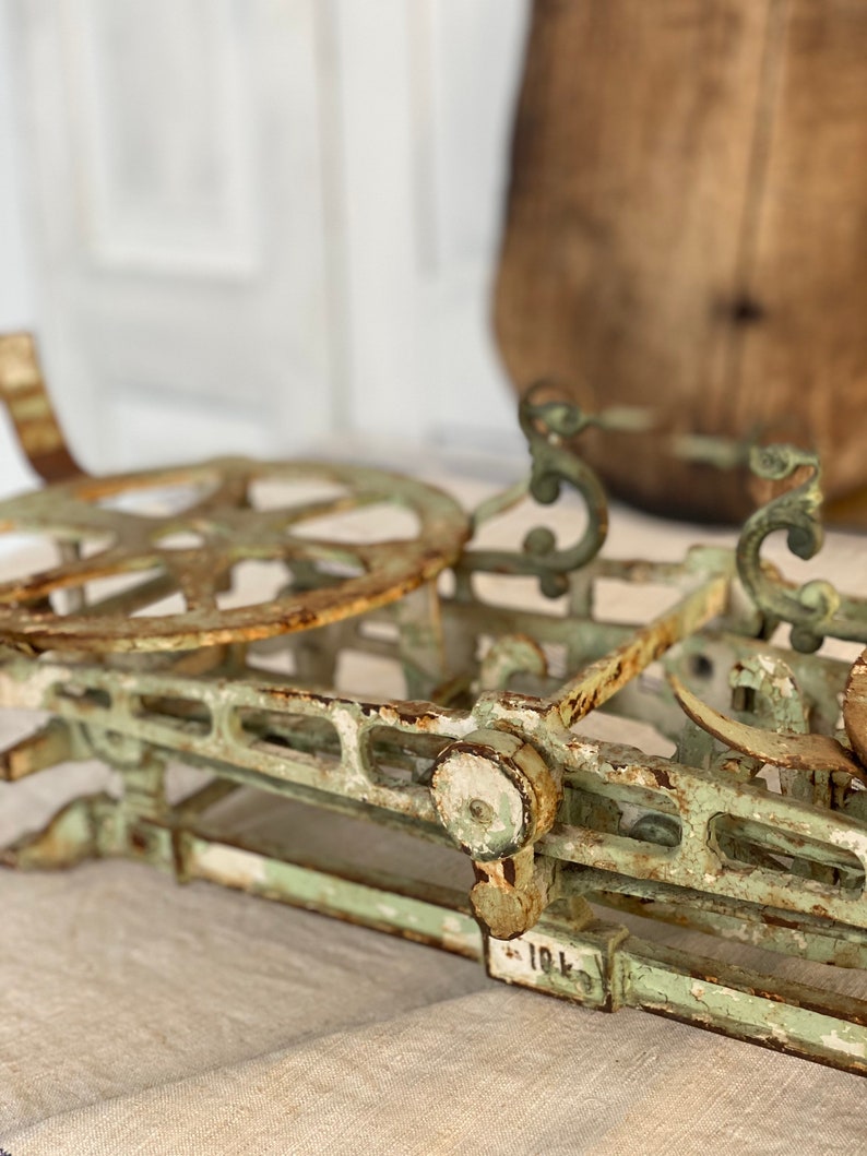 Pu&ograve; includere: Una bilancia vintage in metallo verde con una ruota arrugginita e dettagli decorativi. La bilancia ha una superficie verniciata di bianco con alcuni scheggiamenti ed &egrave; etichettata "10L".
