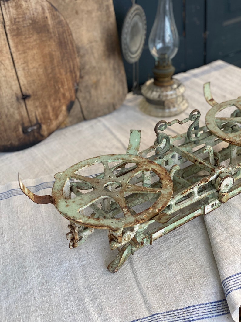 Pu&ograve; includere: Una bilancia vintage in metallo verde con due piattaforme circolari. La bilancia ha una finitura arrugginita ed &egrave; in buone condizioni.