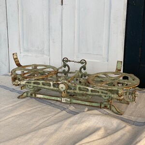 Pu&ograve; includere: Una bilancia vintage in ghisa verde con due piattaforme circolari e una leva centrale. La bilancia presenta dettagli intricati ed &egrave; contrassegnata dal numero "181".