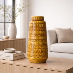 Puede incluir: Jarrón alto de cerámica amarillo mostaza con un patrón geométrico. El jarrón cilíndrico tiene una base acampanada y un cuello estrecho. Un artículo decorativo para el hogar, de unos 40 cm de altura.