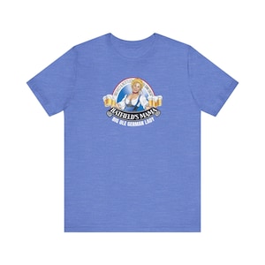 May include: A light blue t-shirt featuring a graphic of a woman in traditional German attire, with the text "Hatfield's Mama Big Ole German Lady" and the words "Brewed & Bottled San Diego". The design includes beer steins.