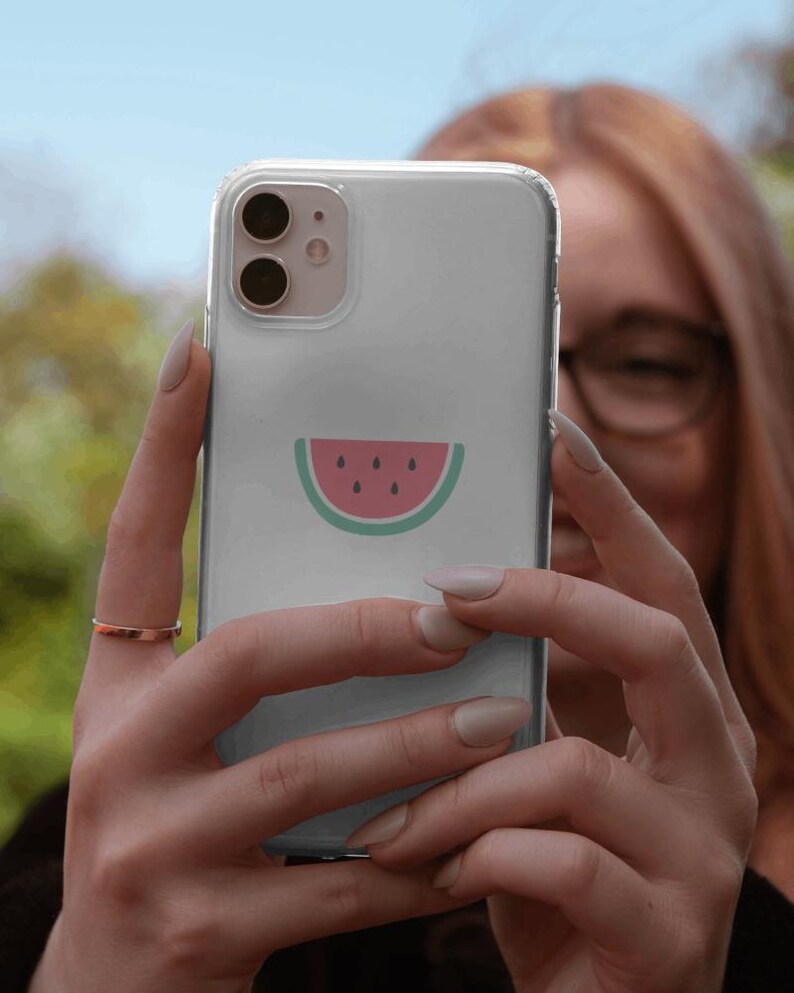 May include: A clear phone case with a watermelon design. The watermelon is pink with black seeds and a green rind.