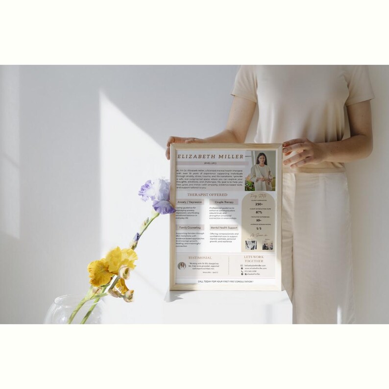 May include: A framed poster with a beige background and brown text. The poster features a woman's headshot, the text "ELIZABETH MILLER", and a list of "THERAPIES OFFERED".