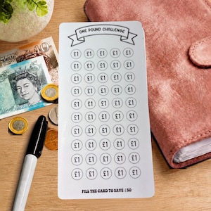 Peut inclure: Une carte de suivi d'épargne rectangulaire blanche avec le texte ONE POUND CHALLENGE en haut et FILL THE CARD TO SAVE £50 en bas. La carte présente une grille de cinquante icônes circulaires, chacune marquée du symbole £1 pour le suivi.