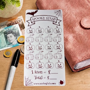 Peut inclure: Une carte de suivi d'épargne rectangulaire blanche avec une encre rouge foncé présentant le texte SPOOKY STASH, une chauve-souris, une toile d'araignée et vingt icônes de citrouille. Le bas indique 1 icon = £, Total = £ et une URL.