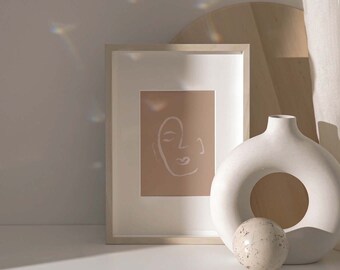 May include: A white ceramic vase with a circular cutout, a small white orb, and a framed print of a line drawing of a face on a beige background.