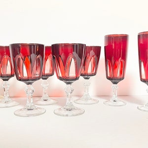 May include: Set of eight red wine glasses with a clear glass stem and base. The glasses have a faceted design.