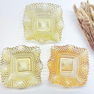 May include: Three square glass dishes with a diamond pattern. The dishes are in shades of yellow and amber.