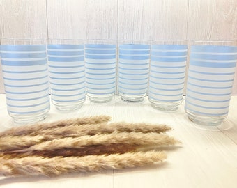 May include: Six clear glass drinking glasses with a blue and white striped pattern. The glasses are arranged in a row on a white surface.