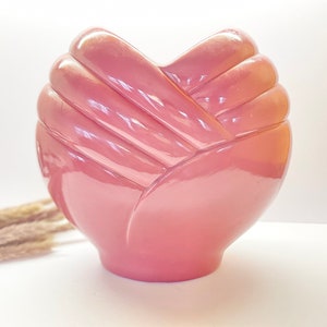 May include: A pink ceramic vase shaped like a heart with a textured, folded design.