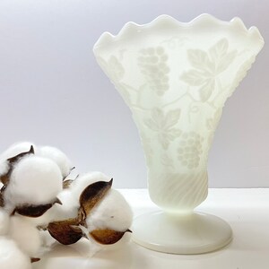 Peut inclure: Vase en verre de lait blanc avec un motif de vigne. Le vase a un bord festonné et un pied en piédestal.
