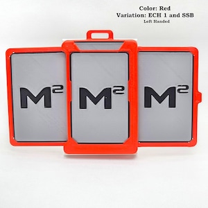 May include: A set of three rectangular badge holders with bright red frames and grey inserts. Each insert features the black text M2. The top of the center holder has a small loop for attachment. Text above reads: Color: Red, Variation: ECH 1 and SSB, Left Handed.