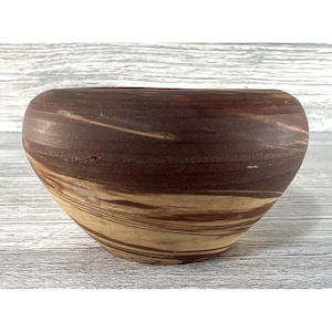 May include: A handcrafted, brown and tan ceramic bowl with a unique, swirled pattern. The bowl has a wide, oval shape and a smooth, polished finish. The color palette includes shades of brown and tan, creating a natural, earthy aesthetic. This decorative bowl is suitable for home decor.