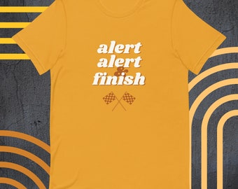 May include: Yellow t-shirt with the text "alert alert & finish" in white with a retro font. Two brown and white chequered racing flags are crossed below the text.