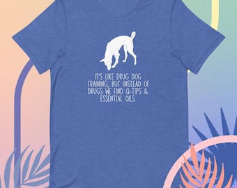 May include: A blue t-shirt with a white silhouette of a dog sniffing the ground. The text "IT'S LIKE DRUG DOG TRAINING, BUT INSTEAD OF DRUGS WE FIND Q-TIPS & ESSENTIAL OILS." is printed on the shirt.