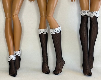 May include: Three pairs of black fishnet stockings with white lace trim at the top. The stockings are worn by three dolls with brown skin.