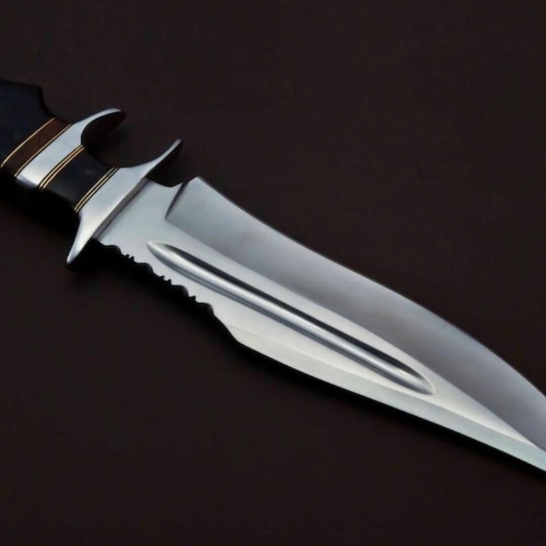 May include: A silver knife with a black and brown handle. The blade has a serrated edge and a pointed tip.