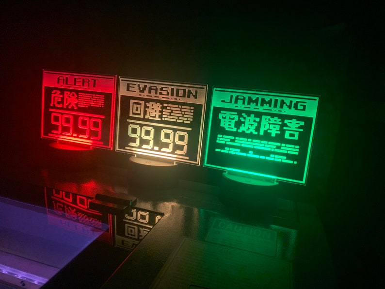 May include: Three illuminated signs with red, white, and green lights. The signs read "ALERT 99.99", "EVASION 99.99", and "JAMMING 電波障害".