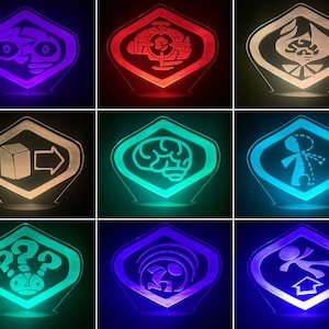 May include: Nine different colored light-up signs with geometric shapes and symbols. The signs are in a grid pattern with three rows and three columns. The signs are lit up in different colors, including red, blue, green, and white.