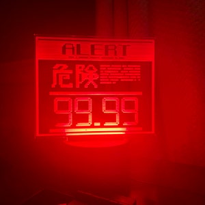 May include: A red LED sign with the word "ALERT" and the text "99.99" in a digital font. The sign is lit up and has a red glow.
