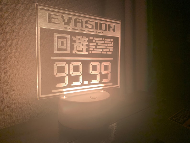 May include: A white acrylic sign with the word "EVASION" and a pixelated image of a square with a circle inside, and the number "99.99" displayed in a pixelated font.