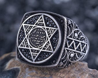 May include: A silver ring with a black star of David design. The ring is set with black stones and has intricate details.