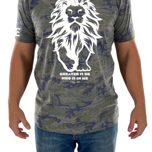 May include: A green, blue, and gray camouflage t-shirt with a white lion graphic and the text "GREATER IS HE WHO IS IN ME 1 John 4:4".