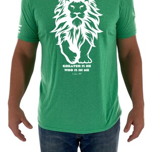 May include: A green t-shirt with a white lion graphic and the text "GREATER IS HE WHO IS IN ME" with the scripture reference "1 John 4:4".