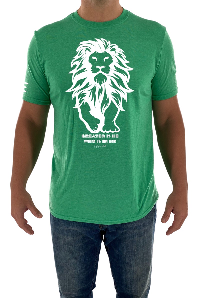 May include: A green t-shirt with a white lion graphic and the text "GREATER IS HE WHO IS IN ME" with the scripture reference "1 John 4:4".