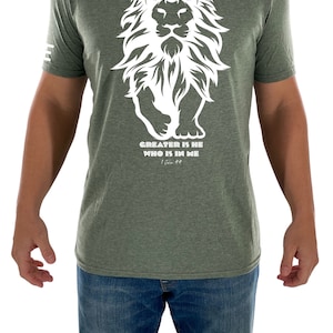 May include: A green t-shirt with a white lion graphic and the text "GREATER IS HE WHO IS IN ME" with the scripture reference "1 John 4:4".